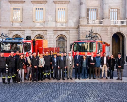 Els integrants del comboi acompanyats de les autoritats a la plaça Sant Jaume. Darrere, una de les autobombes i un camió dels Bombers de Barcelona.
