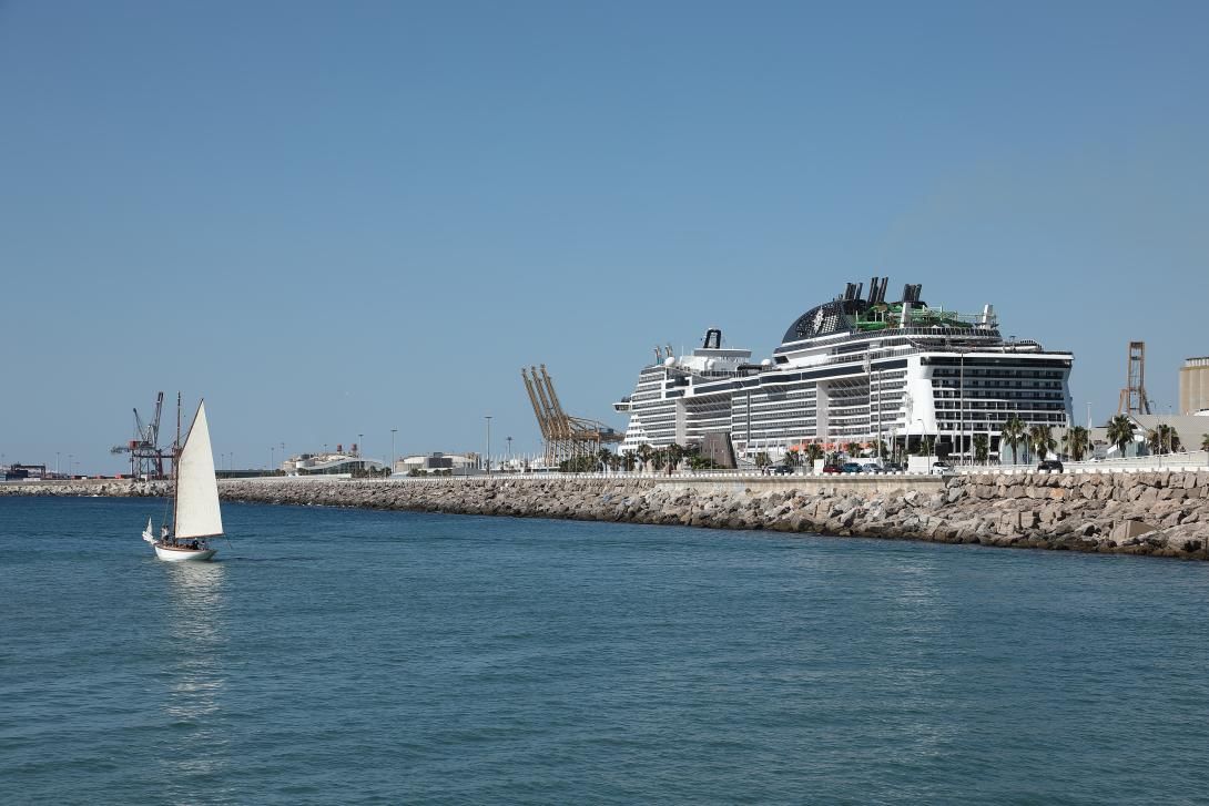 Un veler recreatiu navega amb el moll Adossat de fons