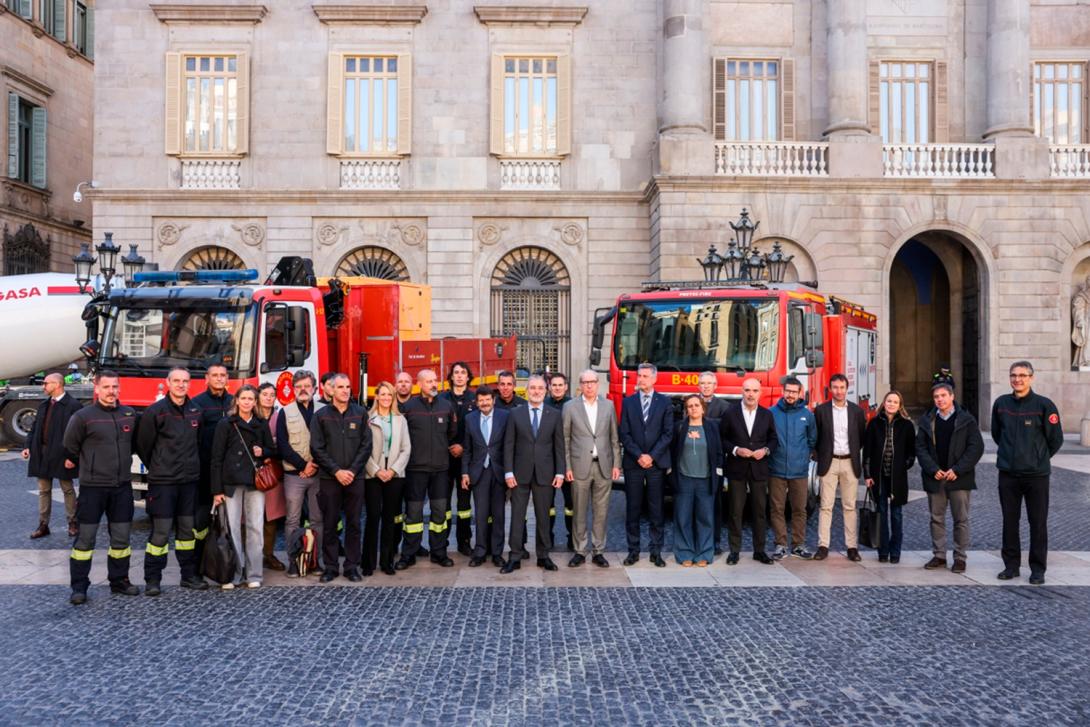 Los integrantes del convoy acompañados de las autoridades en la plaza Sant Jaume. Detrás, una de las autobombas y un camión de los Bomberos de Barcelona. 